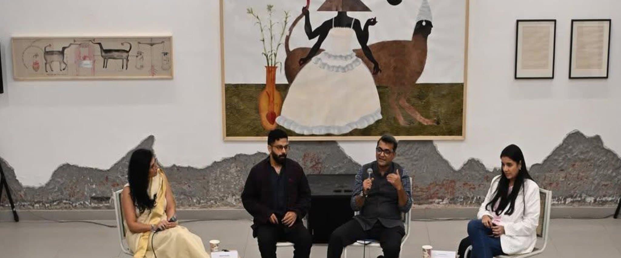 Four speakers seated in conversation in front of paintings at Method Delhi.