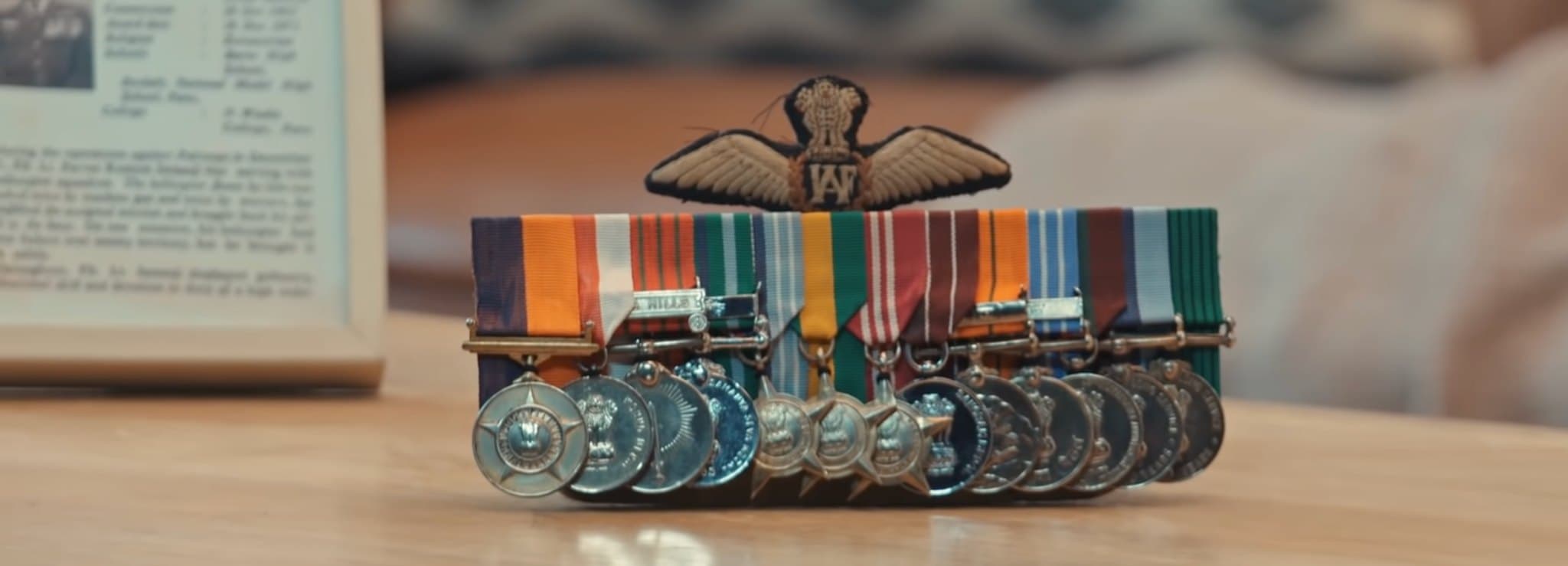 A row of military medals and a winged badge laid out on a table.