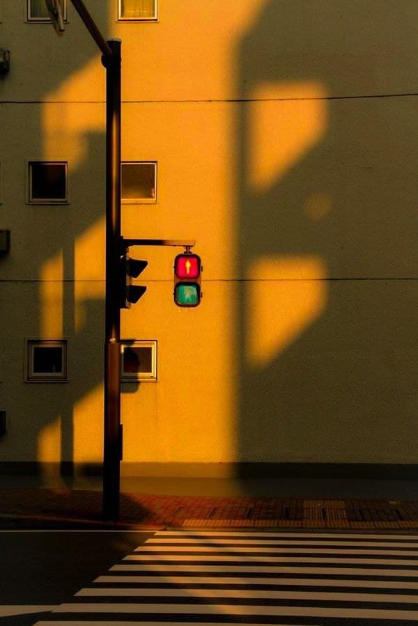 A red traffic light against a building washed in orange evening light.